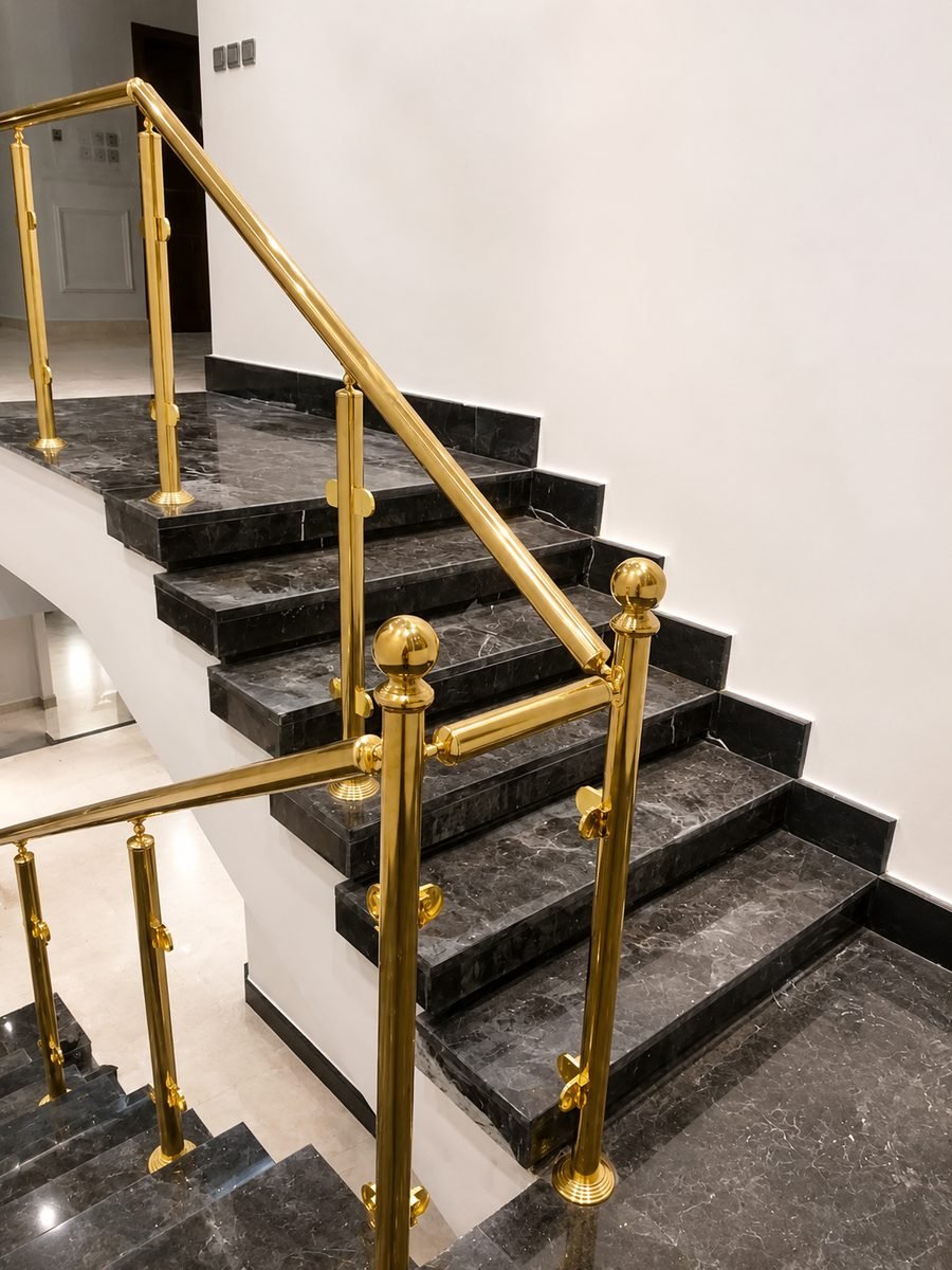 Polished brass handrail and ball-topped posts on black marble stairs